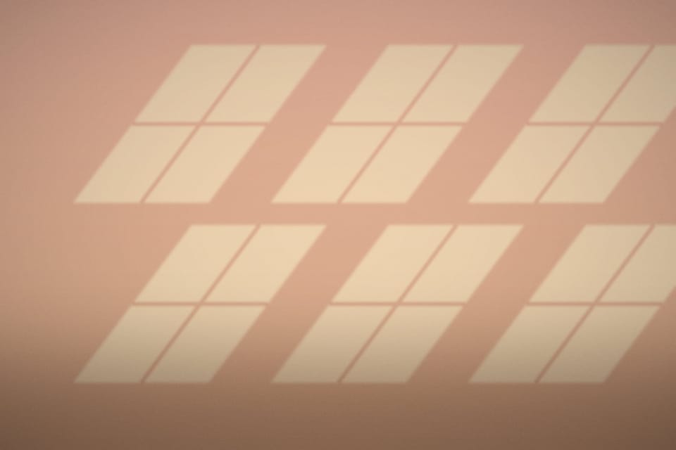 Warm panes of window light across a plaster wall
